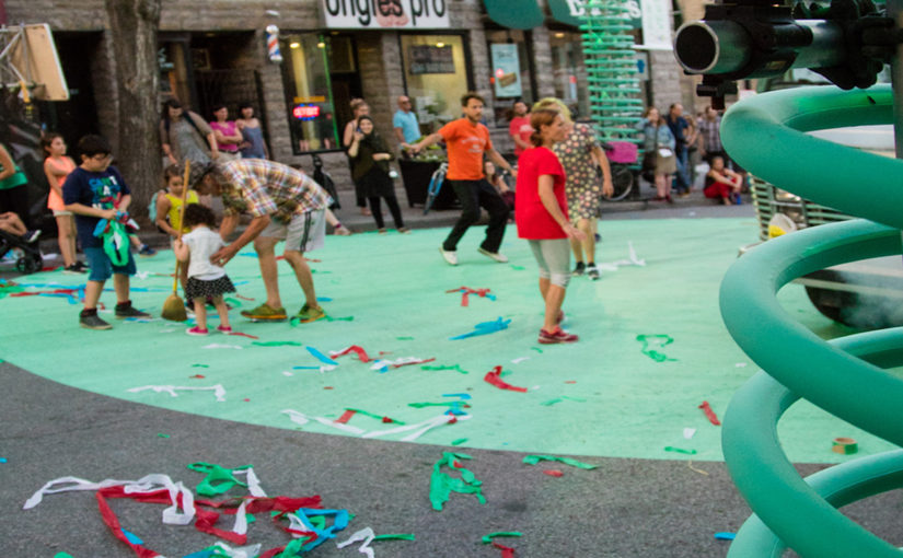 Familles célébrant dans la rue pleine de confettis après une performance de théâtre urbain sur la scène décorée de spring géant
