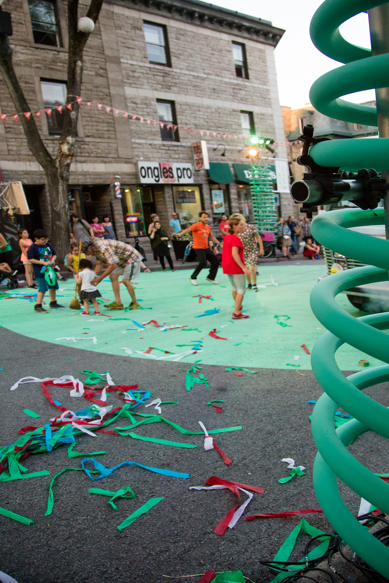 Familles célébrant dans la rue pleine de confettis après une performance de théâtre urbain sur la scène décorée de spring géant