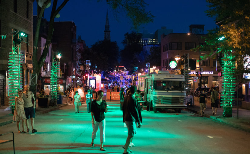 Piétons se promenant la nuit sur la chaussée dans la zone de scène colorée d’un éclairage vert, entourés de springs géants