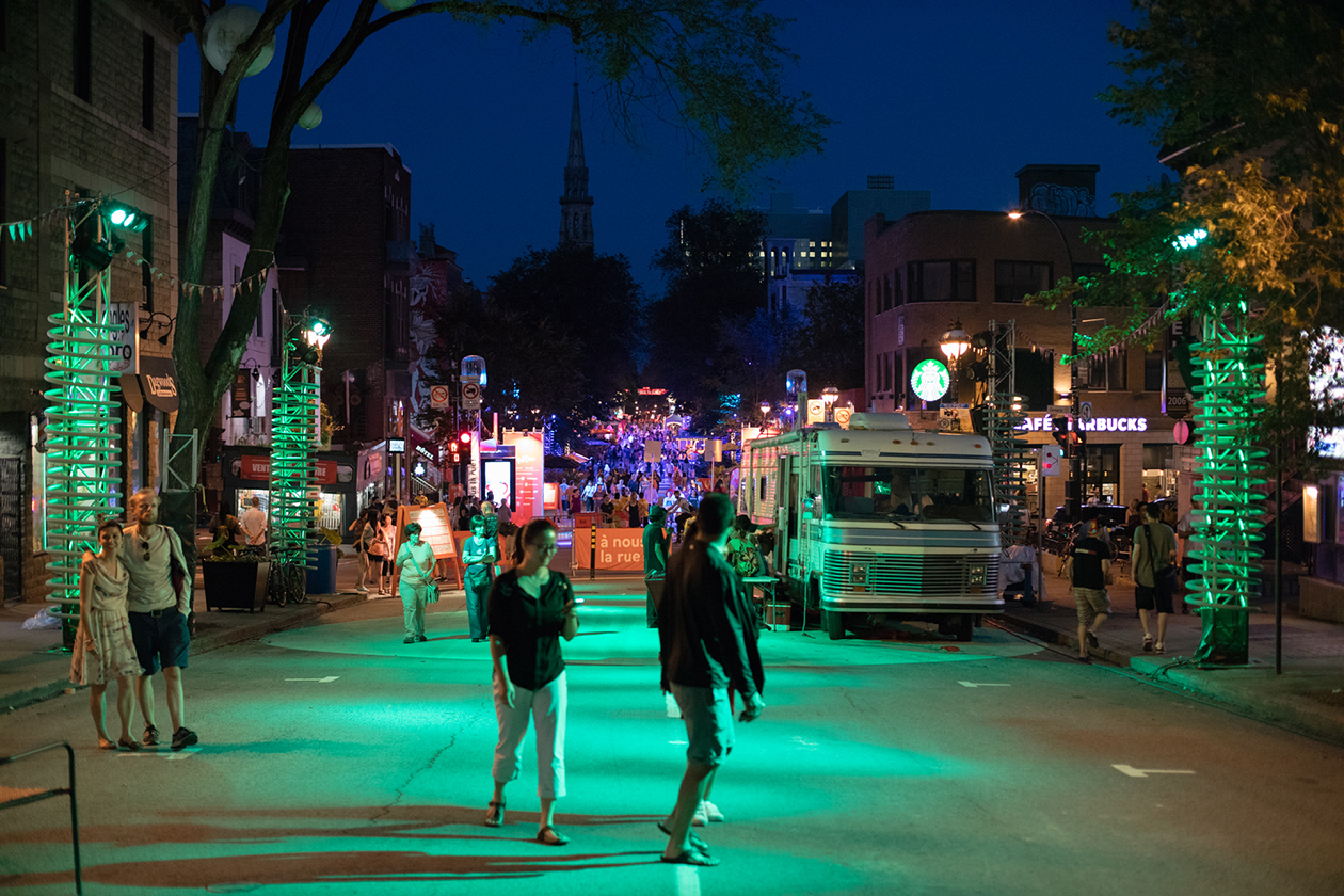 Piétons se promenant la nuit sur la chaussée dans la zone de scène colorée d’un éclairage vert, entourés de springs géants
