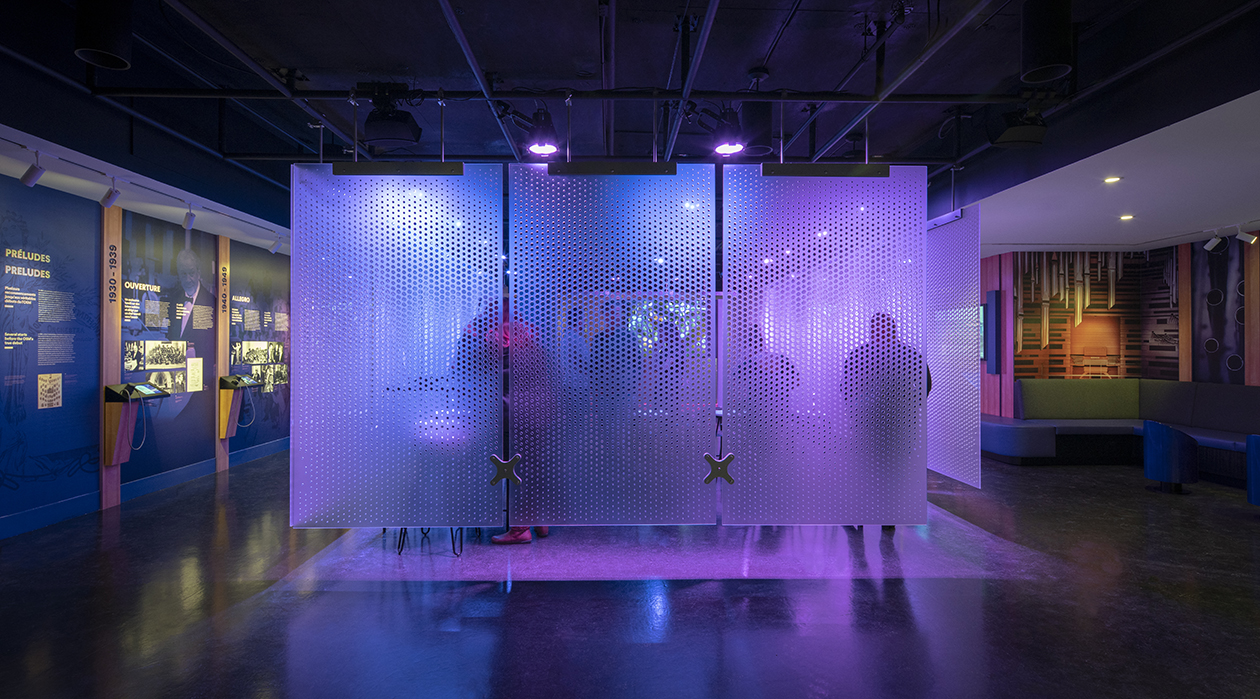 Groupe sous un éclairage diffus participant à une activité immersive derrière une cloison transparente accrochée au plafond